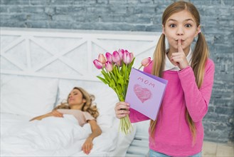 Daughter with tulips greeting card holding finger lips