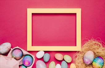 Empty yellow frame with colorful easter eggs pink background