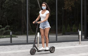 Woman with medical mask riding electric scooter
