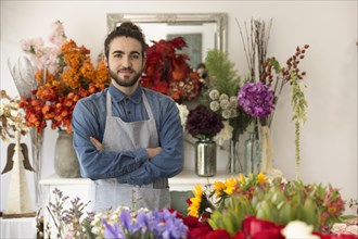 Confident smiling young male florist with colorful flowers his shop