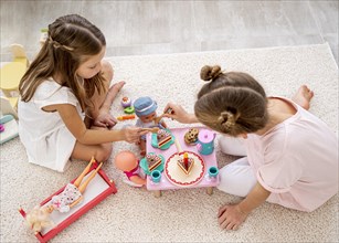 Non binary children playing birthday game with baby dolls
