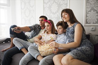 Family eating popcorn during watching television home