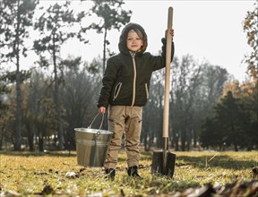 Front view young boy outdoors holding bucket shovel