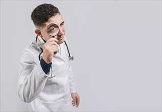 Doctor looking for something with magnifying glass looking isolated. Doctor holding magnifying glass and looking at camera on white background