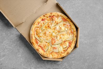 Top view of pizza with blue cheese and slices of pear in cardboard box