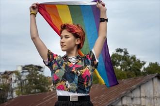 Front view redhead non binary person holding lgbt flag