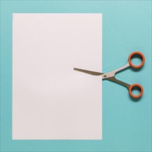 Scissors cutting paper blue background