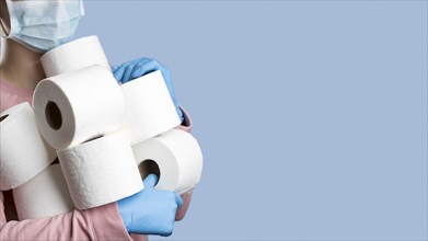 Woman holding toilet paper rolls while wearing surgical gloves medical mask