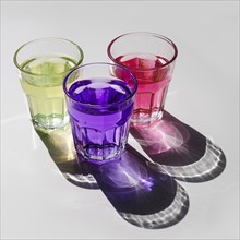 Yellow pink purple drink glasses with shadow white background