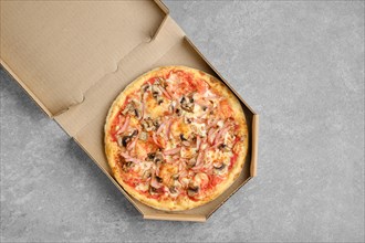 Pizza with ham and champignon mushrooms in cardboard box
