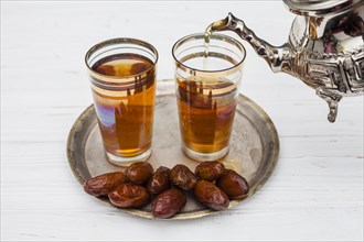 Heap dry dates near cups tea teapot