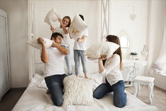 Playful family having funny pillow fight bed