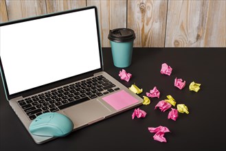 Turquoise mouse adhesive note takeaway cup crumpled paper laptop showing white screen display black background