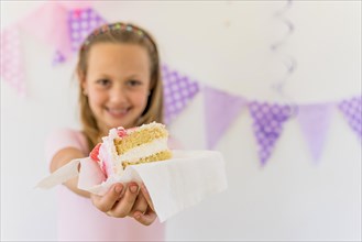 Cute smiling girl giving cake slice birthday part
