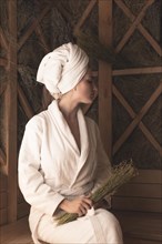 Young woman holding medical herbs relaxing sauna