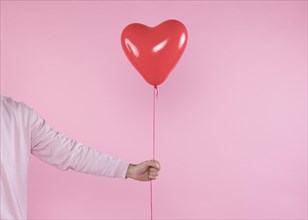Person holding red balloon with twist