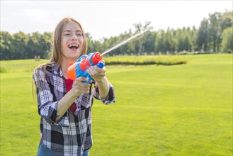 Medium shot cheerful girl playing with water gun