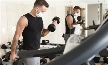 Man working out gym while wearing medical mask