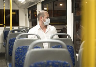 Elegant adult male riding bus with medical mask