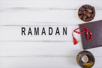 Ramadan text with bowl juicy dates diary red prayer beads white table