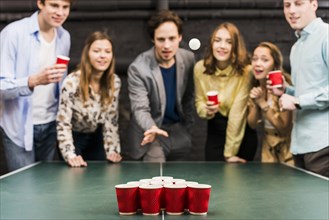 Friends looking ball while man playing beer pong bar