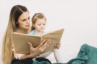 Mother reading book cute girl bed