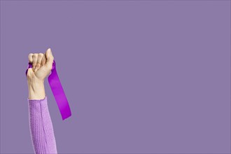 Woman s hand holding violet ribbon copy space