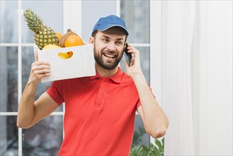 Courier with fruits speaking phone