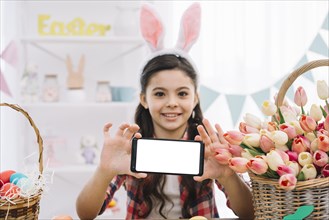 Portrait girl wearing bunny ears showing her smartphone easter day