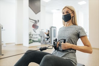 Woman with medical mask working out gym