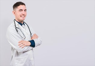Smiling latin doctor with crossed arms on isolated background. Cheerful doctor with crossed arms isolated. Portrait of young doctor with arms crossed