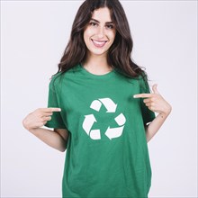 Smiling young woman green t shirt showing recycle icon