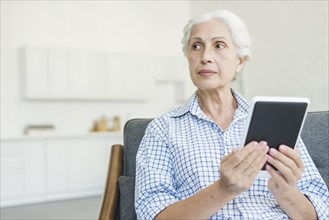 Senior woman holding digital tablet looking away