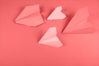 Coral pink paper airplane colored background