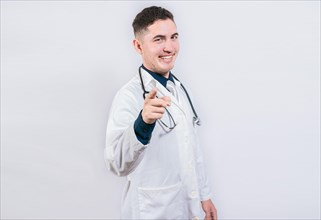 Handsome doctor pointing at the camera. Friendly and smiling doctor pointing at you