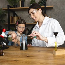 Girl female teacher doing science experiments with microscope
