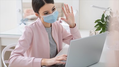 Young business woman working from home wearing mask
