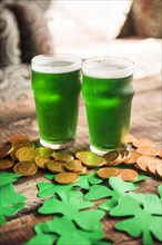 Glasses green drink near heap coins paper shamrocks