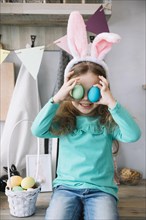 Cute girl bunny ears holding colored eggs eyes