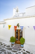 White Greek Orthodox church with colourful flags