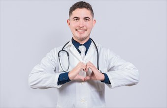 Friendly doctor making heart gesture with hands isolated. Young latin doctor making heart shape on isolated background
