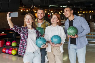 Friends holding colorful bowling balls