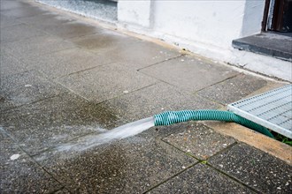 Water is pumped out of a cellar through a hose after a thunderstorm