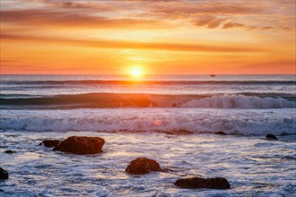 Atlantic ocean sunset with waves and rocks at Costa da Caparica