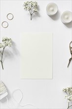 Blank card surrounded with gypsophila wedding rings string scissor white background