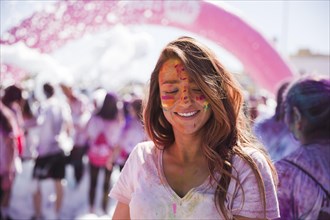 Portrait smiling young woman with holi color face