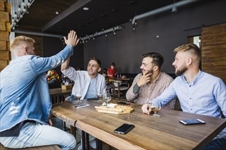 Young man giving high five his friends restaurant