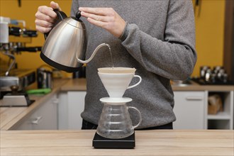 Front view male barista pouring hot water coffee filter
