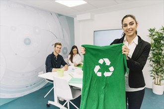 Portrait happy young businesswoman showing green t shirt with recycle icon