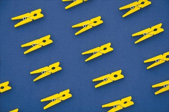 Flat lay yellow clothes pins blue background